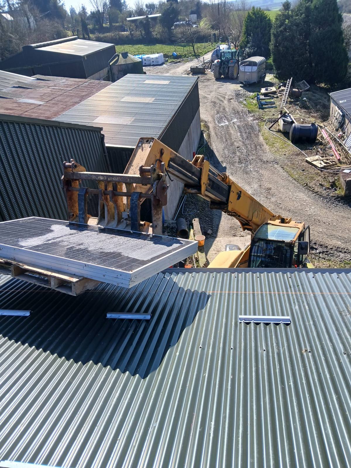 Telehandler lifting a pallet of solar panels to a roof in Co. Cork, installed by CTS Solar